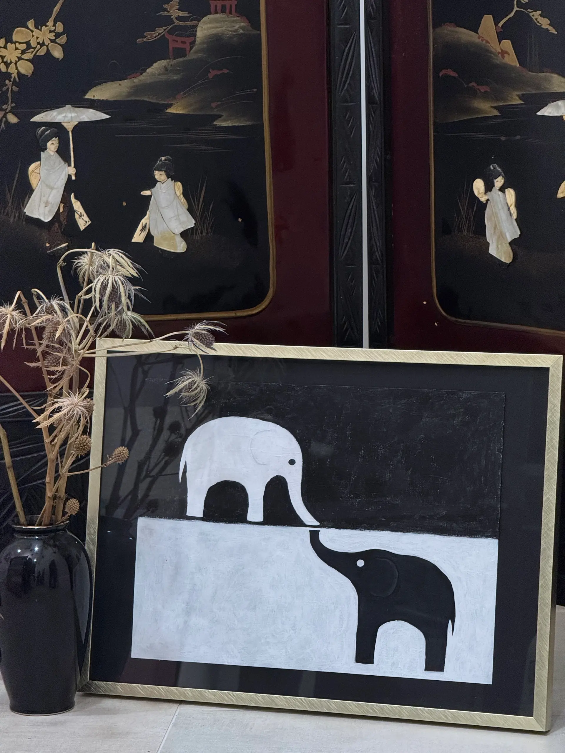 A graphic black and white painting of two elephant silhouettes.