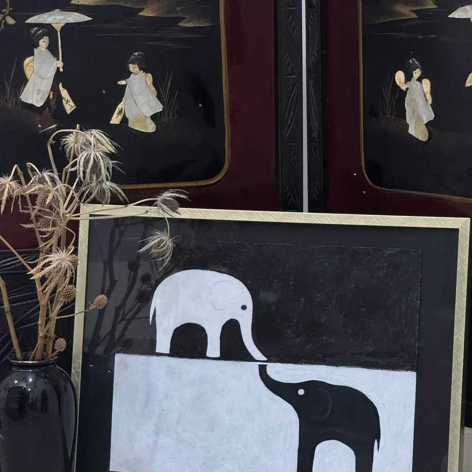 A graphic black and white painting of two elephant silhouettes.