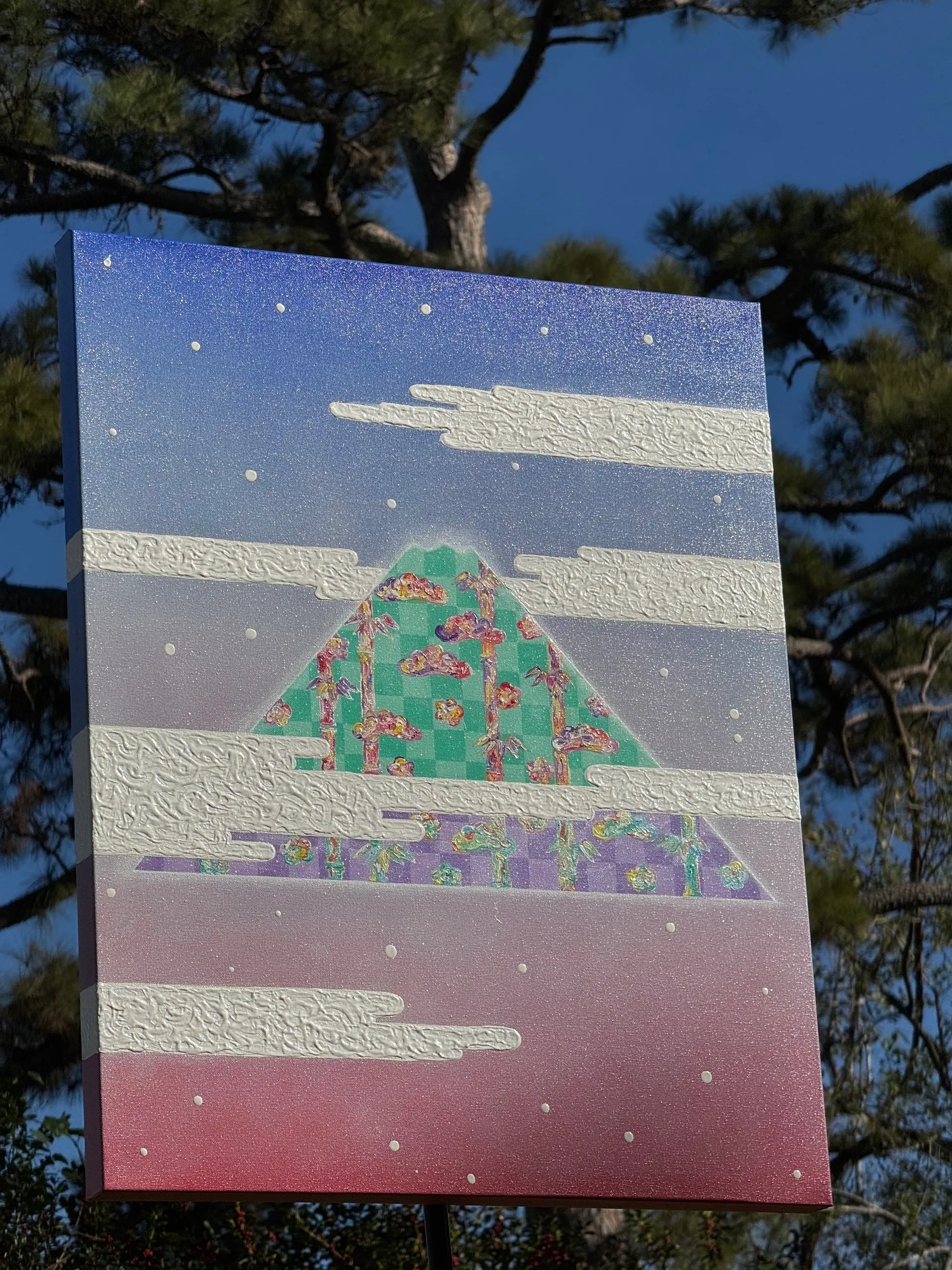A layered landscape painting with a central green hill beneath bands of blue, pink, and white.