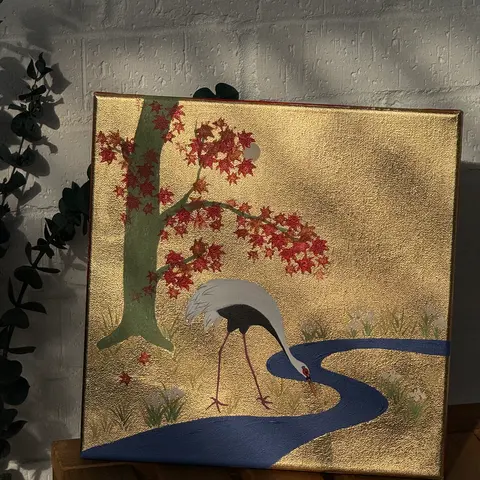 A white crane by a blue stream beneath a red maple tree on a gold ground.